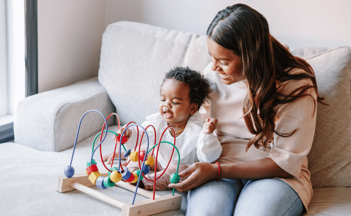 mother playing with toddler on couch