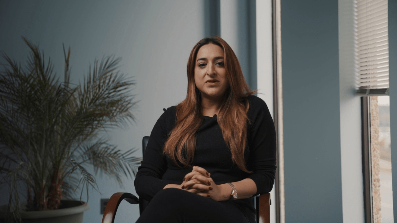 Sarah Ahmed, seated in a bright office setting with a potted plant and window in the background, participates in SAAAC Autism Centre's Autism 101 campaign to promote awareness and acceptance of autism.